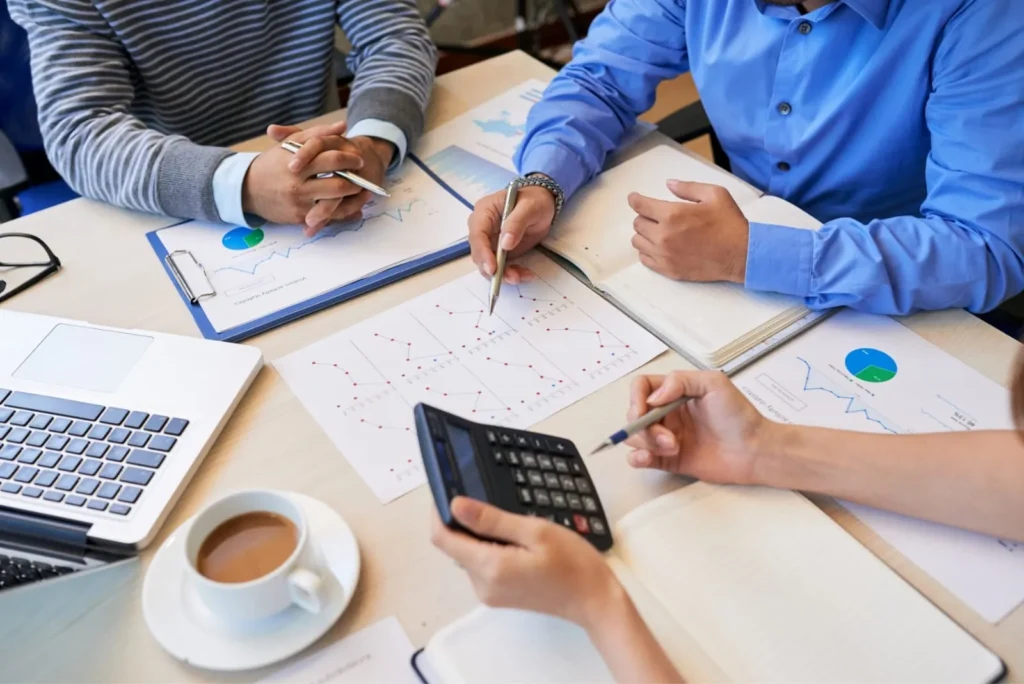 Besprechung mit Finanzberichten, Taschenrechner und Laptop – Unternehmensberatung in Innsbruck